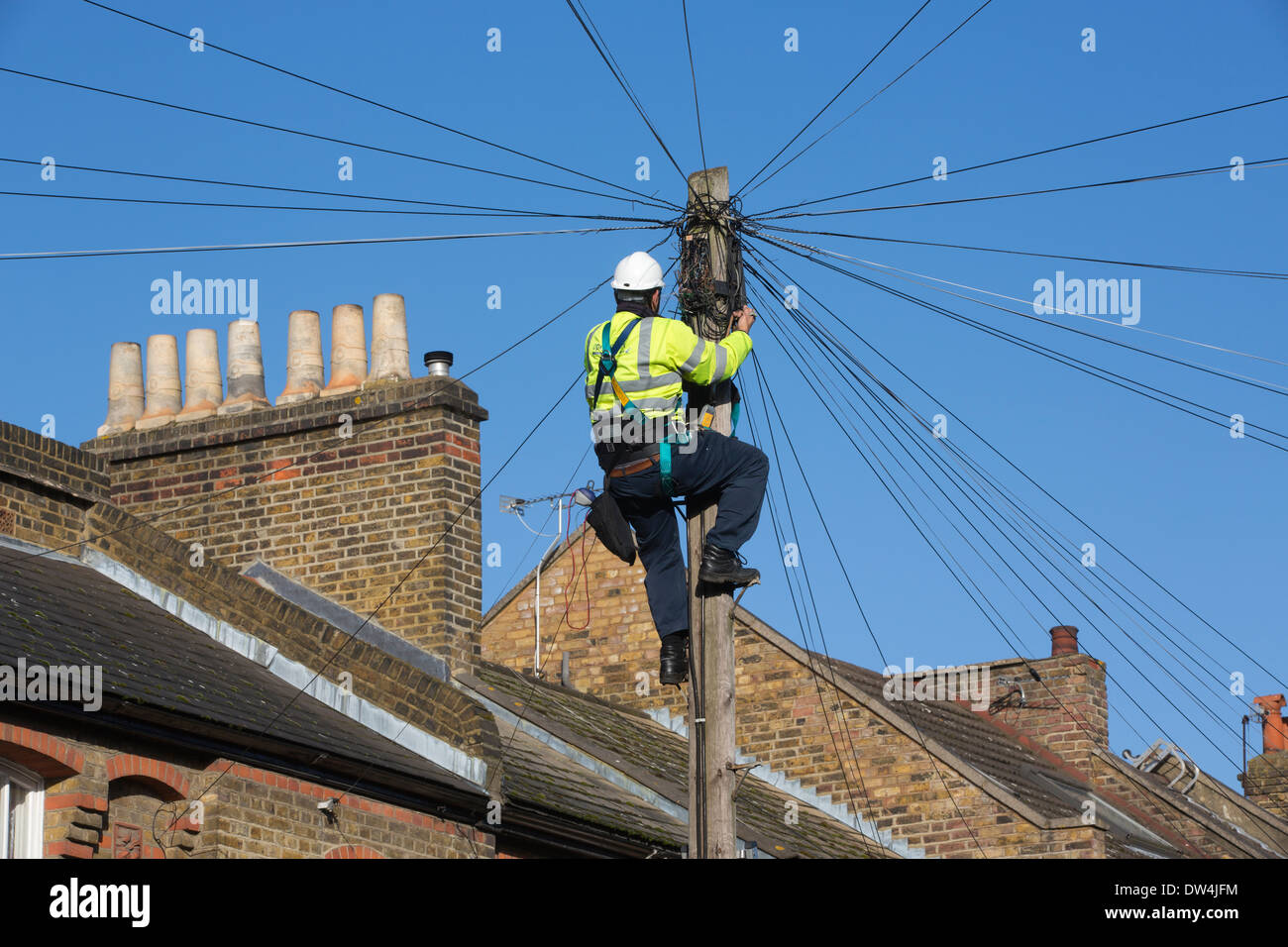 Telekommunikation Ingenieur arbeitet auf eine obenliegende Telefonmast Kommunikation unter Reihenhäuser in London, Großbritannien Stockfoto