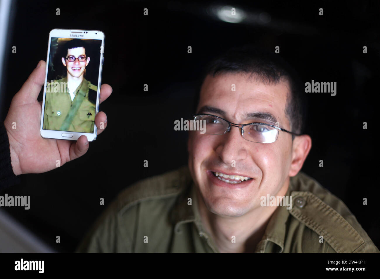 Gaza, Palästinensische Gebiete. 27. Februar 2014. Majed Jundiyeh Direktor hält ein Mobiltelefon, das Bild von Gilad Schalit, der Gestalt des Schauspielers Mahmoud Karira zu vergleichen, die den Charakter von Shalit in einen Film im Gaza-Streifen namens "Verlieren Shalit" spielen wird. "Schalit verliert", derzeit in dem abgeriegelten Gebiet gefilmt wird, ist der erste einer geplanten dreiteiligen Serie über die 2006 Aufnahme des israelischen Soldaten Gilad Schalit von bewaffneten verbündete sich mit den islamischen Militanten Hamas-Bewegung. Teile zwei und drei werden Schalits Zeit in Gefangenschaft und seine 2011 Swap für Hunderte von palästinensischen Pr darzustellen. Stockfoto