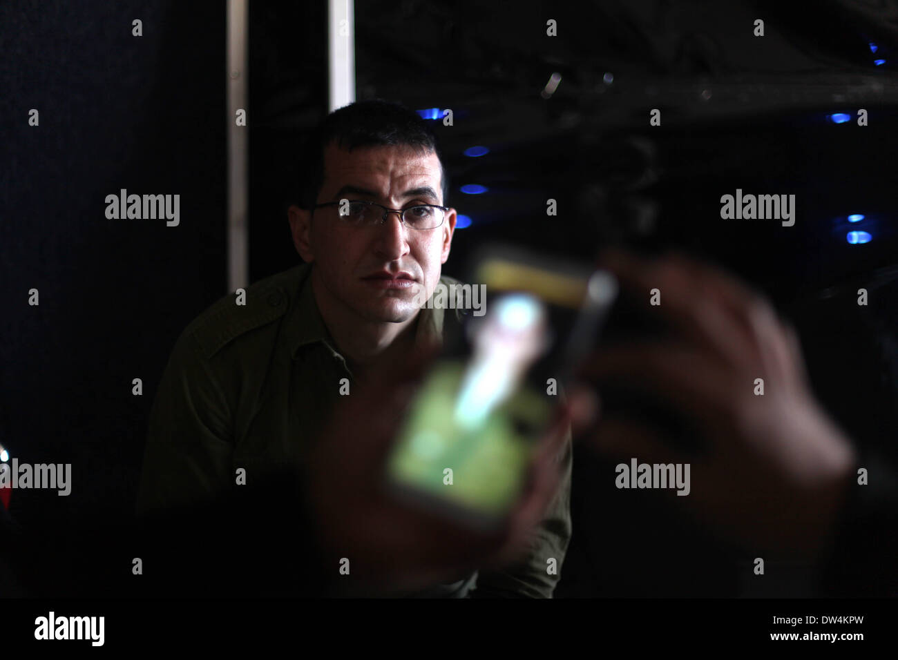 Gaza, Palästinensische Gebiete. 27. Februar 2014. Majed Jundiyeh Direktor hält ein Mobiltelefon, das Bild von Gilad Schalit, der Gestalt des Schauspielers Mahmoud Karira zu vergleichen, die den Charakter von Shalit in einen Film im Gaza-Streifen namens "Verlieren Shalit" spielen wird. "Schalit verliert", derzeit in dem abgeriegelten Gebiet gefilmt wird, ist der erste einer geplanten dreiteiligen Serie über die 2006 Aufnahme des israelischen Soldaten Gilad Schalit von bewaffneten verbündete sich mit den islamischen Militanten Hamas-Bewegung. Teile zwei und drei werden Schalits Zeit in Gefangenschaft und seine 2011 Swap für Hunderte von palästinensischen Pr darzustellen. Stockfoto
