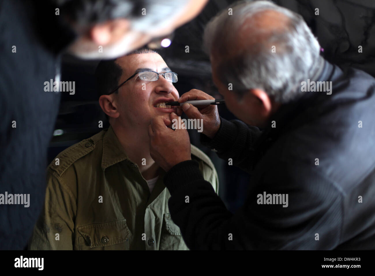 Gaza, Palästinensische Gebiete. 27. Februar 2014. Schauspieler Mahmoud Karira, der Gilad Schalit spielt, hat Make-up angewendet von einem Assistenten während der Dreharbeiten eines Films im Gaza-Streifen namens "Verlieren Shalit" gemacht. "Schalit verliert", derzeit in dem abgeriegelten Gebiet gefilmt wird, ist der erste einer geplanten dreiteiligen Serie über die 2006 Aufnahme des israelischen Soldaten Gilad Schalit von bewaffneten verbündete sich mit den islamischen Militanten Hamas-Bewegung. Teile zwei und drei werden Schalits Zeit in Gefangenschaft und seine 2011 Swap für Hunderte von palästinensischen Häftlinge durch Israel darzustellen. (Kredit-Bild: © Majdi Fathi/NurPhoto/ZUM Stockfoto