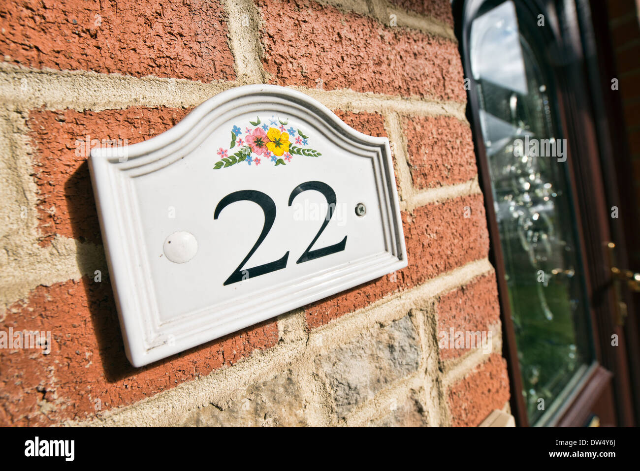 Die Nummer 22 auf einer keramischen Tafel an der Wand durch eine schwarze Tür Stockfoto