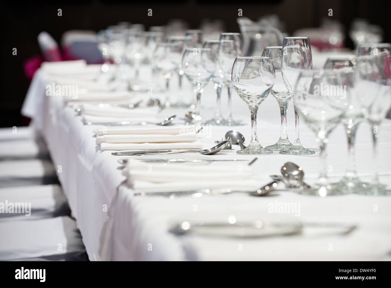 Ein flacher Fokus Bild von einem Bankett Tische Maßgedecke & Weingläser warten auf die Ankunft der Abendessen Stockfoto