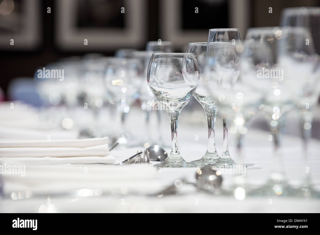 Ein flacher Fokus Bild von einem Bankett Tische Maßgedecke & Weingläser warten auf die Ankunft der Abendessen Stockfoto