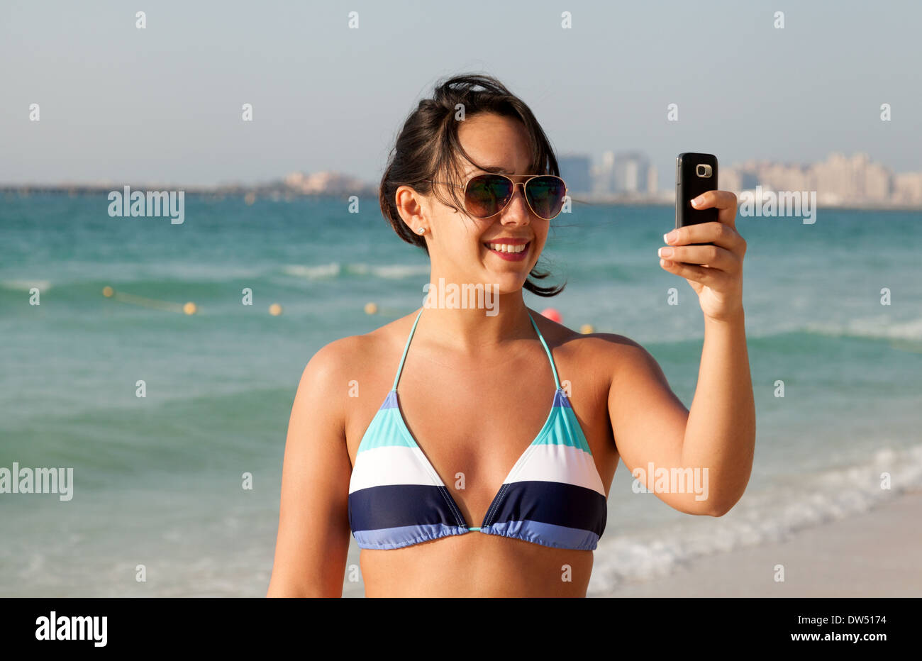 Frau fotografieren Selfie am Strand im Bikini, im Urlaub, Jumeirah Beach, Dubai, Vereinigte Arabische Emirate, Vereinigte Arabische Emirate, Naher Osten Stockfoto