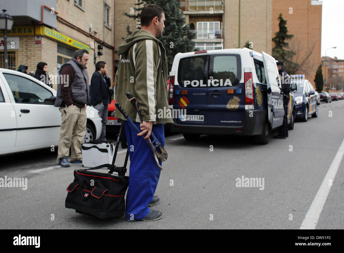 Madrid, Spanien. 27. Februar 2014. Polizei Wache stehen, richtig, da eine Schlosser verlässt mit einem Bolzenschneider und ein Brecheisen als Gehäuse Menschenrechtsaktivisten zwingen die Verschiebung der Carolina Salazar Fernandez Räumung in Madrid, Spanien, Donnerstag, 27. Februar 2014. Carolina Salazar Fernandez, 23 Jahre alt, ist eine alleinerziehende Mutter von zwei Kindern: Jesus, 3 Jahre alt, und Abraham, 6 Jahre alt. Ihr einziges Einkommen, ist es ein Staat nutzen von 530 Euro ($ 723). Sie hat eine leere abgeschotteten Wohnung Besitz SAREB Bank im Februar 2013 besetzt. Sie versucht zu verhandeln, um eine niedrige geschützten Miete, da ihr Einkommen zahlen ist es nicht Stockfoto