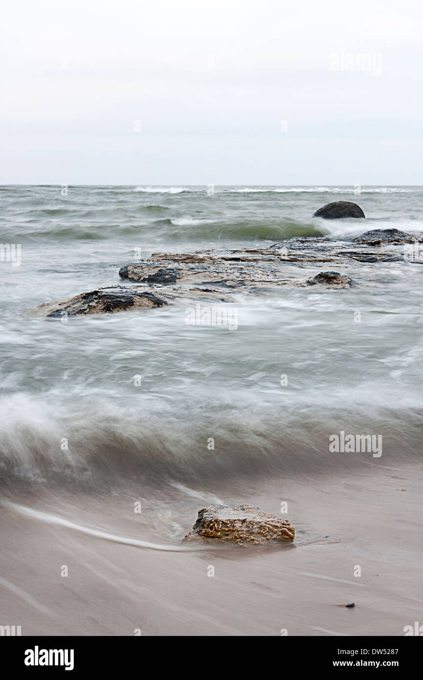 Steinen im welligen Meer an bewölkten Tag Stockfoto