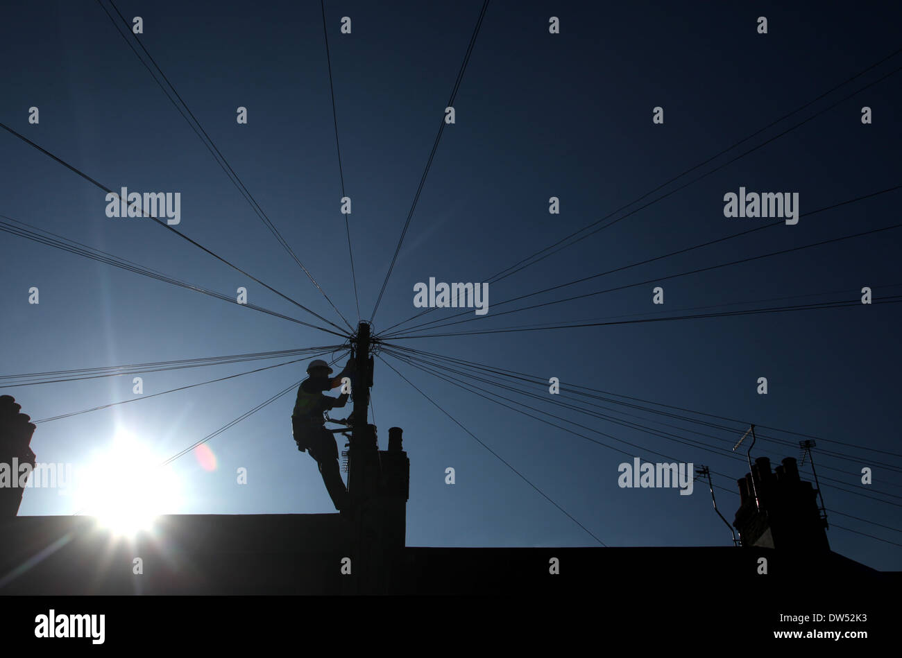 Ein Telekom-Techniker behebt Drähte an die oben auf einer telefonischen Befragung / Silhouette von der Sonne Stockfoto