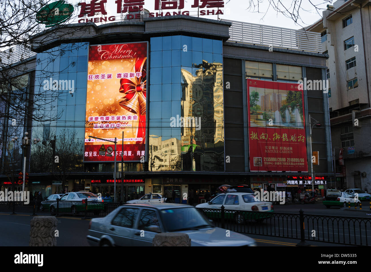 LED-Bildschirm zeigt Frohe Weihnachten wünschen auf die Spiegelung Fenster eines Einkaufszentrums in Chengde. Hebei Provinz, China. Stockfoto