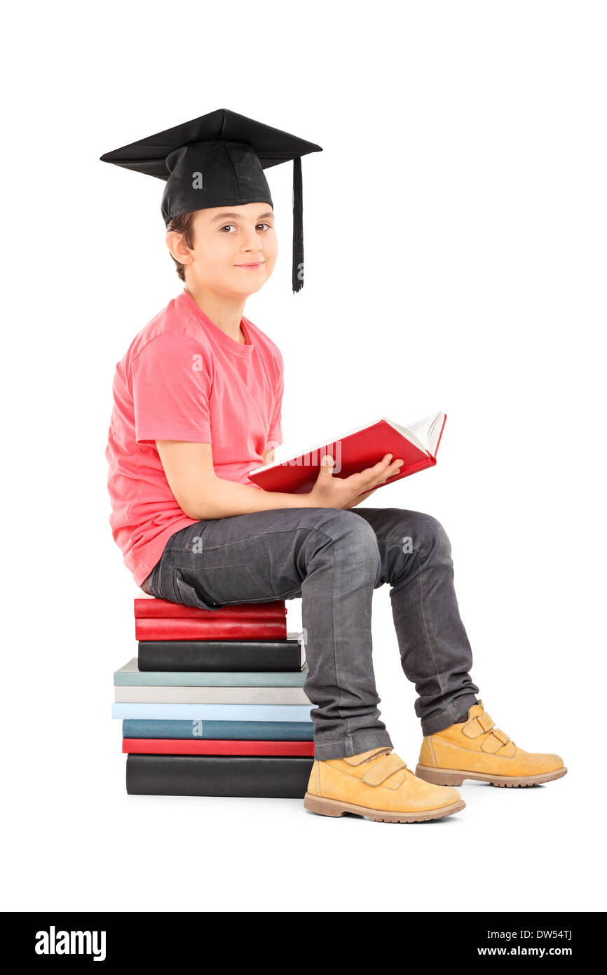 Junge mit Quaste sitzend auf einem Stapel Bücher Stockfoto