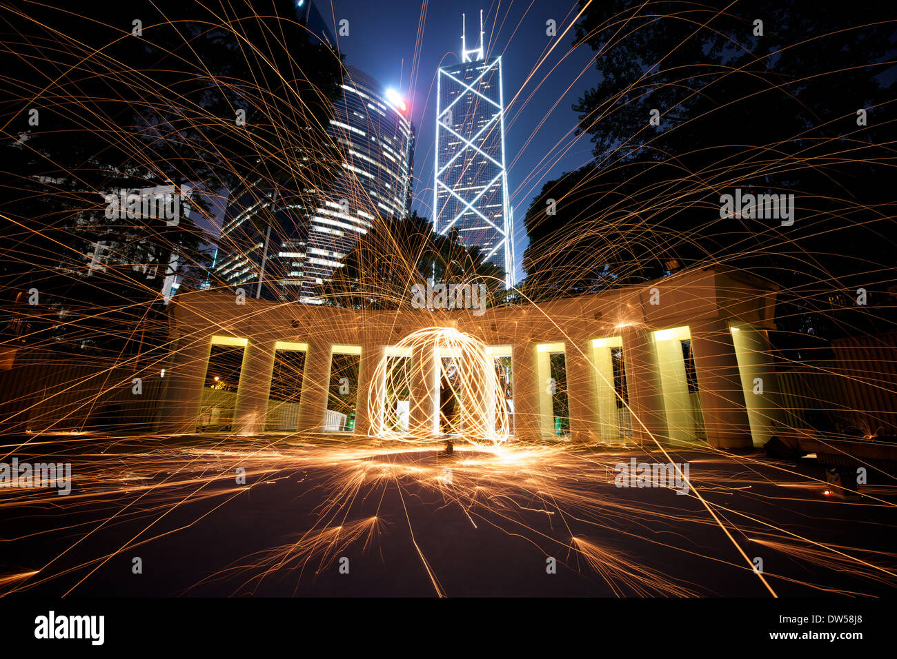 Die Fotografie von Steelwool erfasst die dynamische Bewegung von Funken, die von brennender Stahlwolle fliegen, und erzeugt faszinierende Lichtmuster. Die Technik ist beliebt für atemberaubende visuelle Effekte, die oft nachts mit urbanem Hintergrund fotografiert werden. Stockfoto