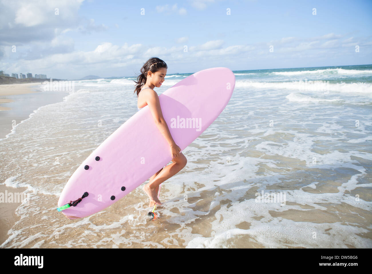 Süße junge Mädchen mit rosa Surfbrett zu Fuß ins Wasser am Strand Stockfoto