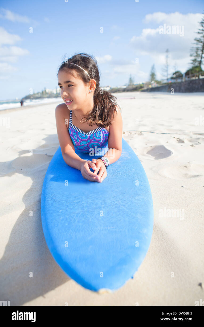 Süße junge Mädchen am blauen Surfbrett am Strand liegen und mit Blick auf Meer Stockfoto