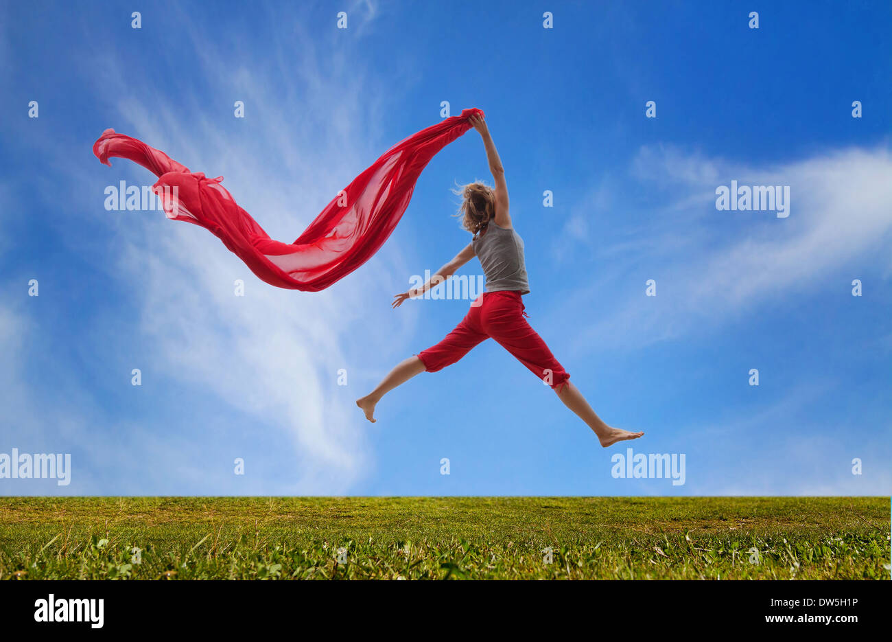 glückliches Mädchen springen mit rotem Stoff Stockfoto