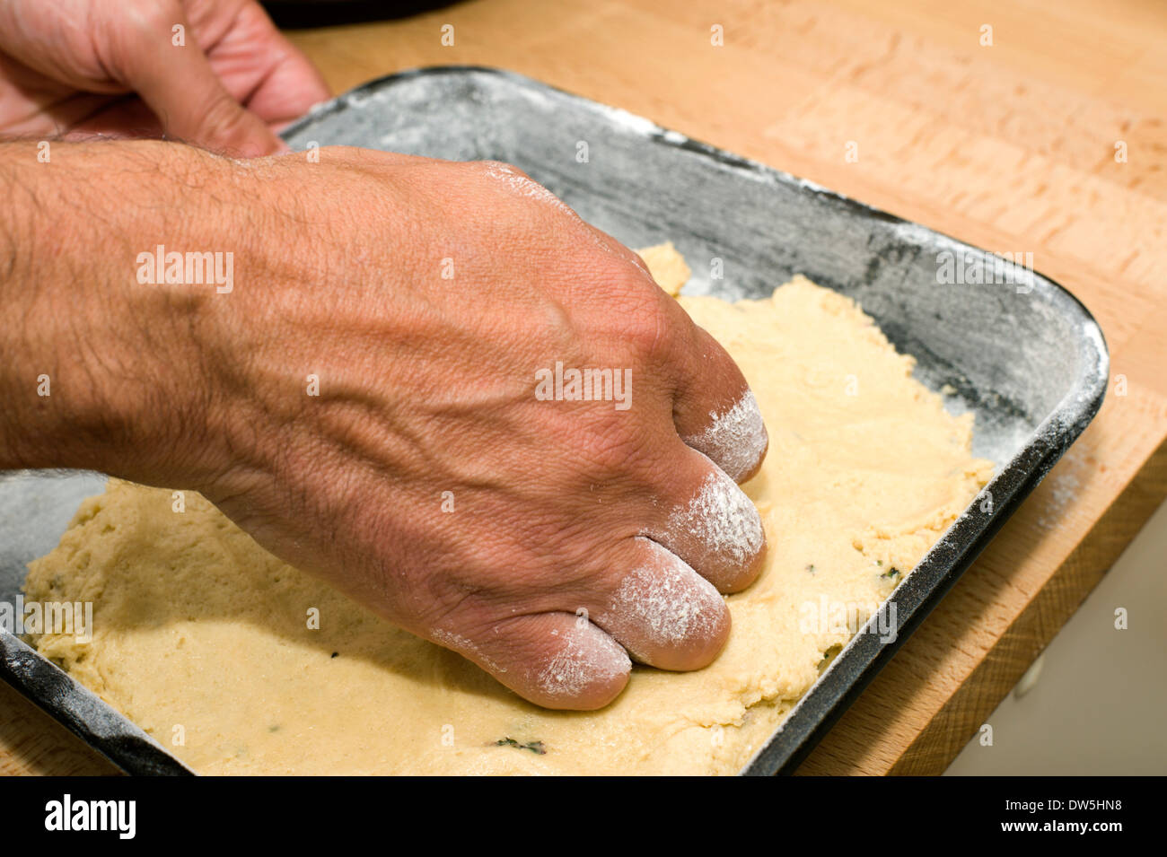 Drücken Sie hausgemachten Kuchen Mischung in einem bemehlten Backblech fertig zum Backen im Ofen Stockfoto