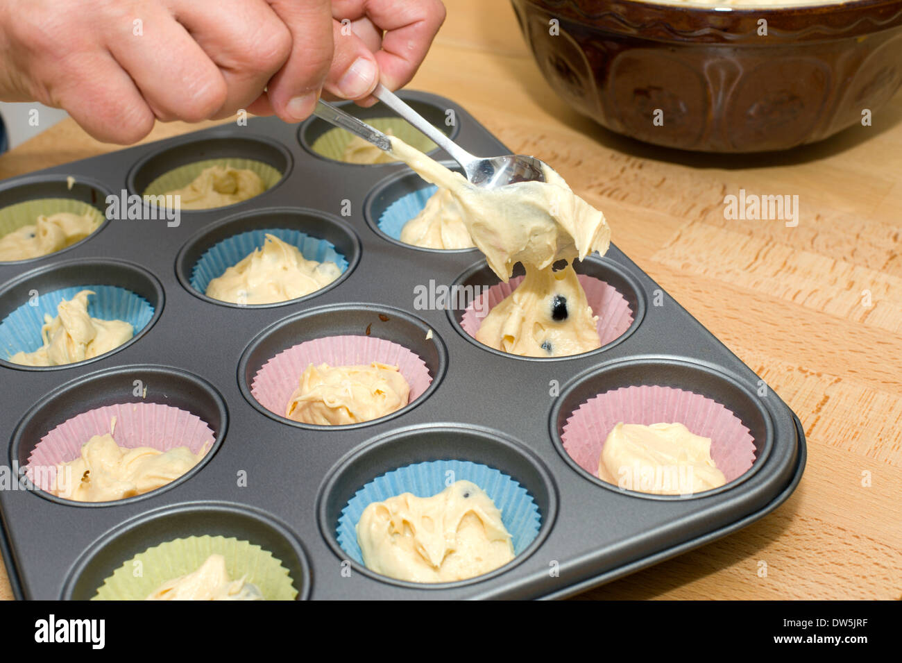 Löffelt einen Kuchenteig in Kuchen Fällen bereit für das Kochen im Ofen Stockfoto