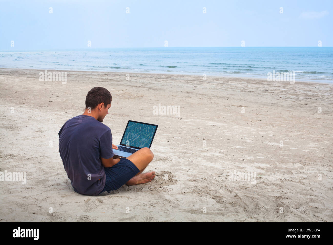 Mann mit Laptop am Strand Stockfoto