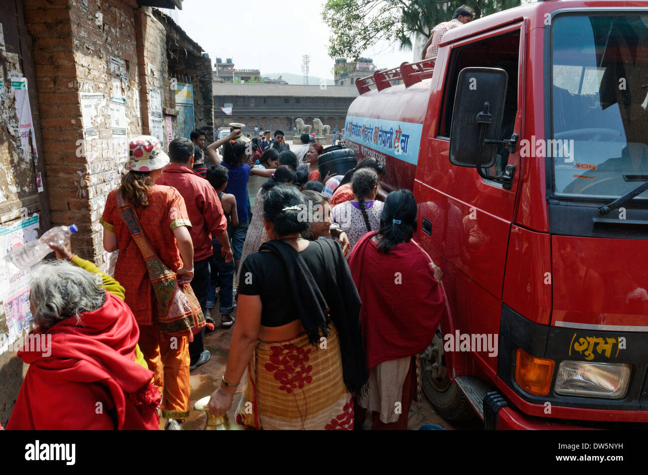 Nepalesische Frauen (und neugierige Touristen) Masse ein frisches Wasser Lieferung runde Lkw in Kathmandu, Nepal Stockfoto