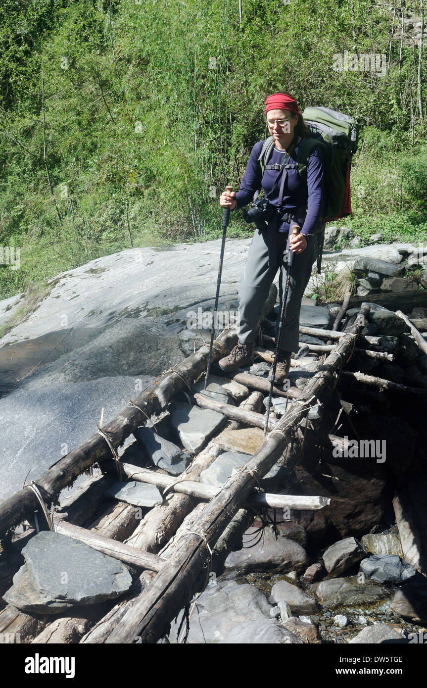 Eine Dame Trekker eine hölzerne Brücke in Nepal Stockfoto