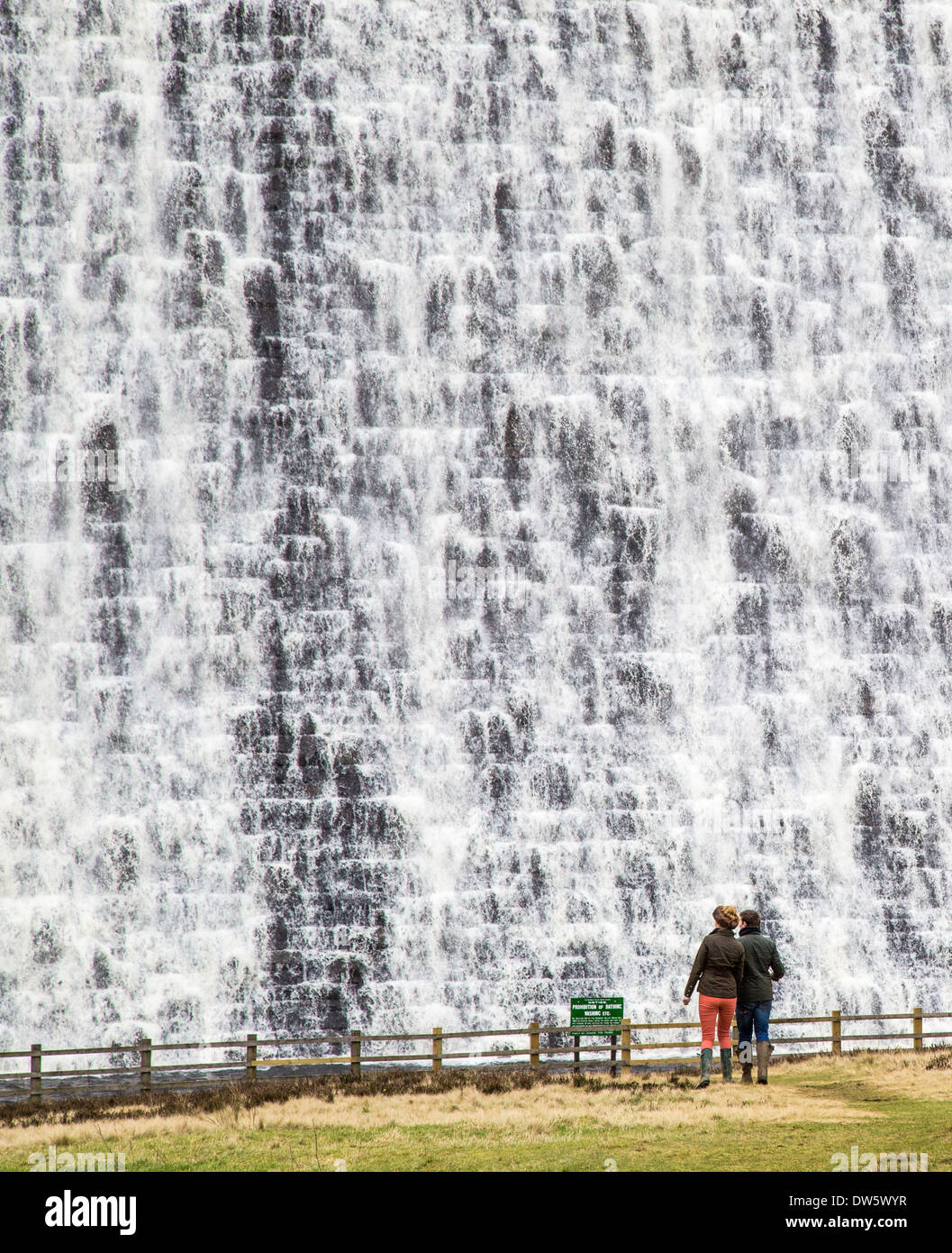 Ein paar zuschauen Wasser überlaufen der Derwent Stausee Staumauer in Derbyshire Peak District nach Wochen von heavy rain Stockfoto