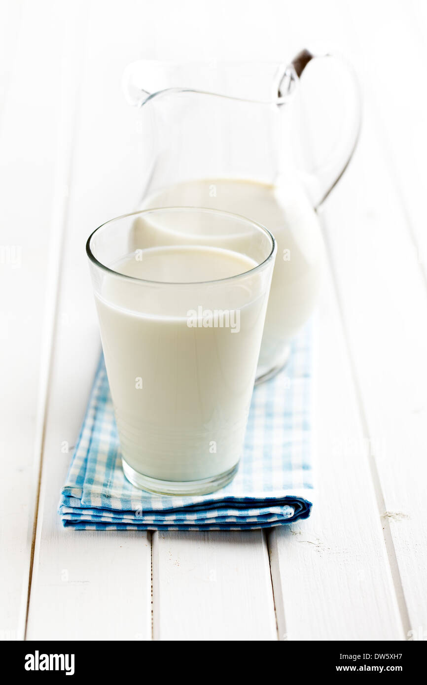 Milch im Glas auf weißer Holztisch Stockfoto