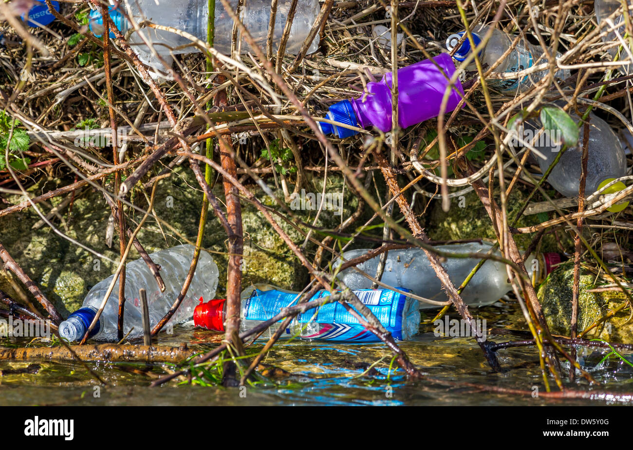 Ausrangierte Plastikflaschen verschmutzen das Ufer eines Flusses. Stockfoto