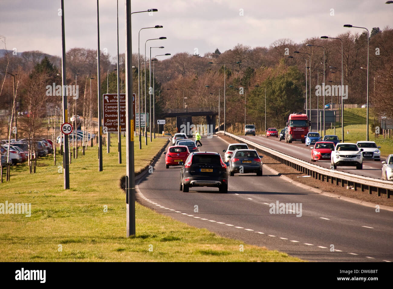 Ein Arbeiter tragen eine gelbe Leuchtweste zu Fuß über der geschäftigen Kingsway West Schnellstraße in Dundee, Großbritannien Stockfoto