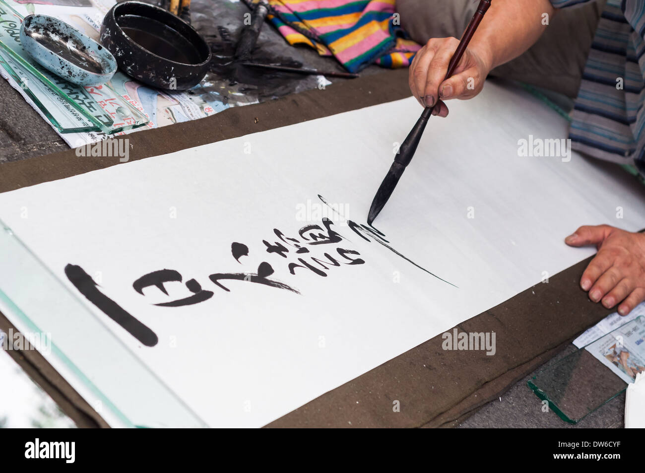 A Street-Artist schreibt Hanja oder chinesische Schriftzeichen, auf ein großes Blatt Papier auf einem Straßenmarkt in Insadong, Seoul. Stockfoto