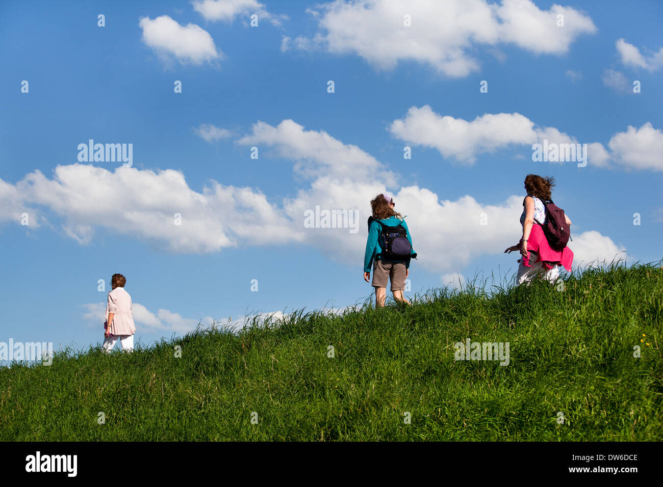 Touristen zu Fuß auf dem Deich, Hintergrund blauer Himmel mit weißen Wolken Stockfoto