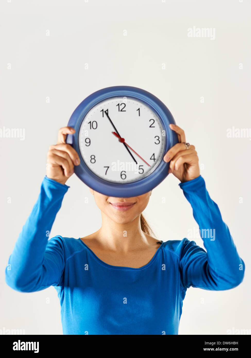 Porträt von asiatischen Geschäftsfrau versteckt sich hinter blauen Uhr und mit Blick auf die Kamera zu Lächeln Stockfoto