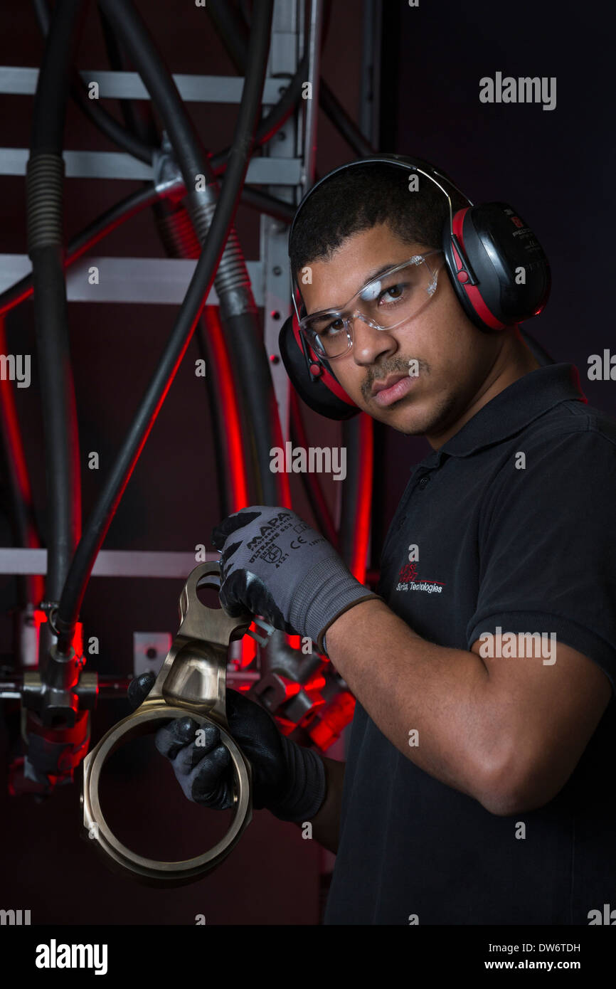 Ein Operator einen Ersatz vor seinem Strahlanlage genauer unter die Lupe nehmen. Opérateur Examinant Une Pièce Mécanique. Stockfoto