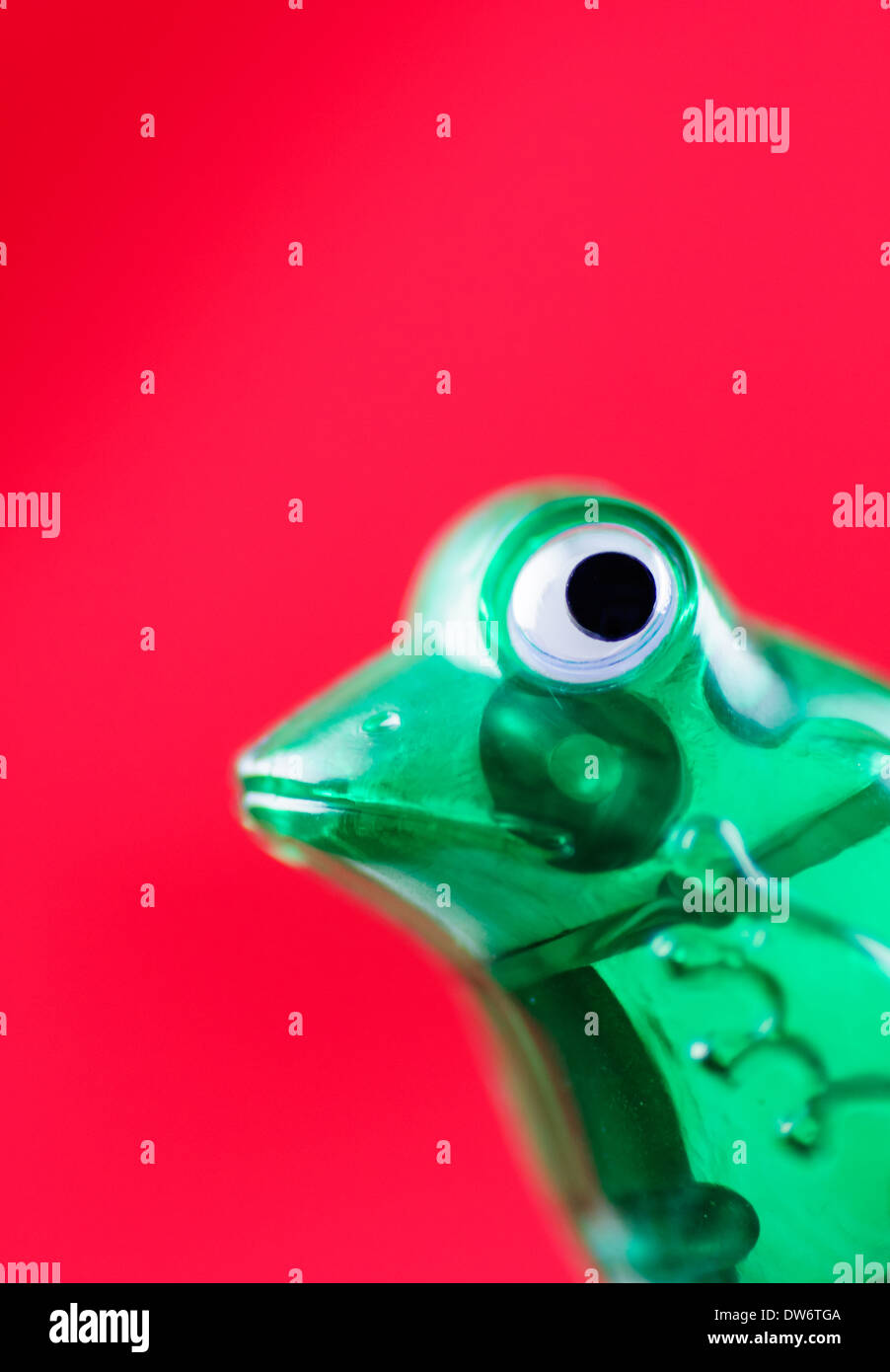 Nahaufnahme eines grünen, Kunststoff Frosch Wind Spielzeug auf rotem Grund Stockfoto