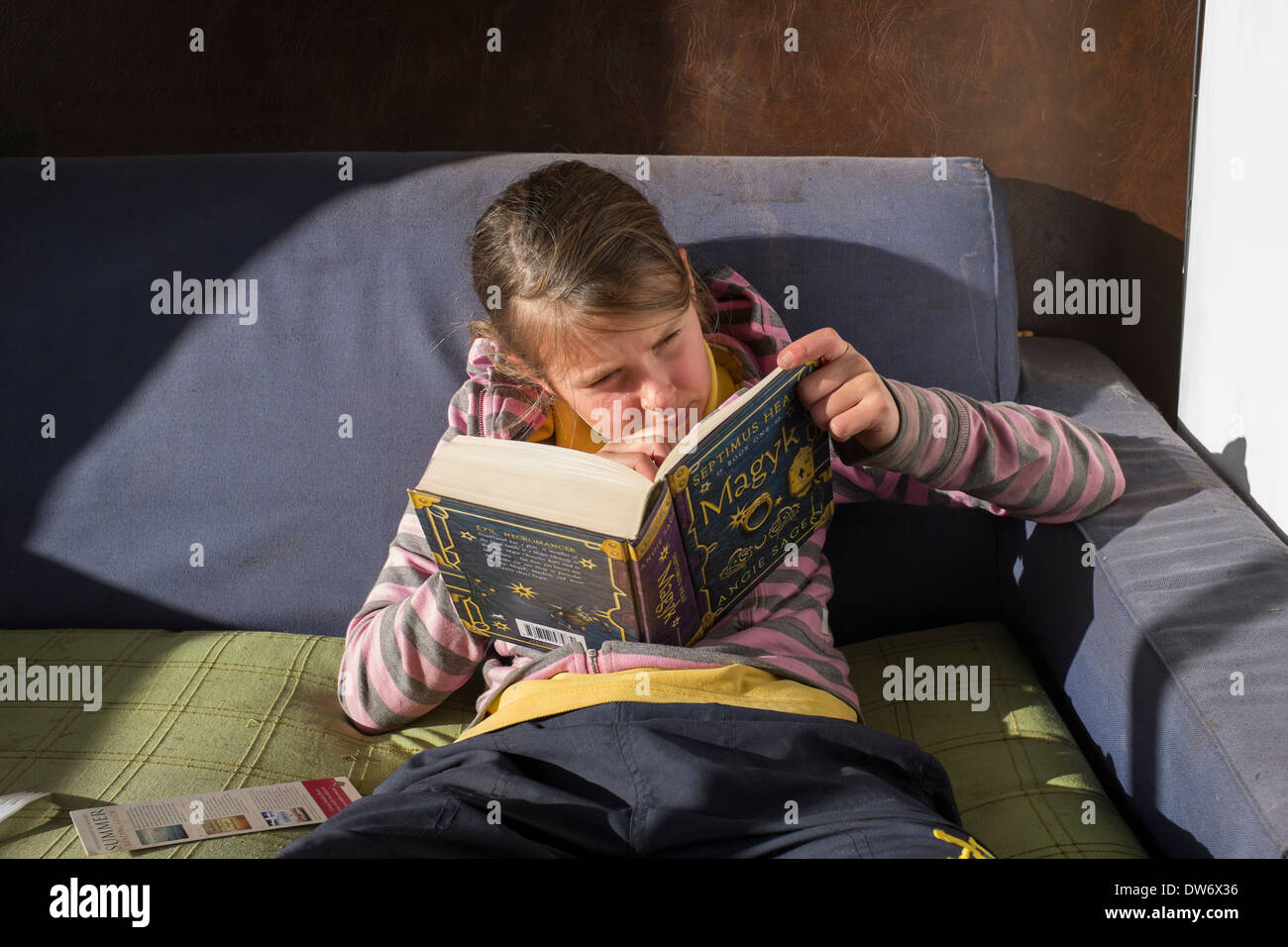 Ein Kind in einem Buch auf der Couch vertieft Stockfoto