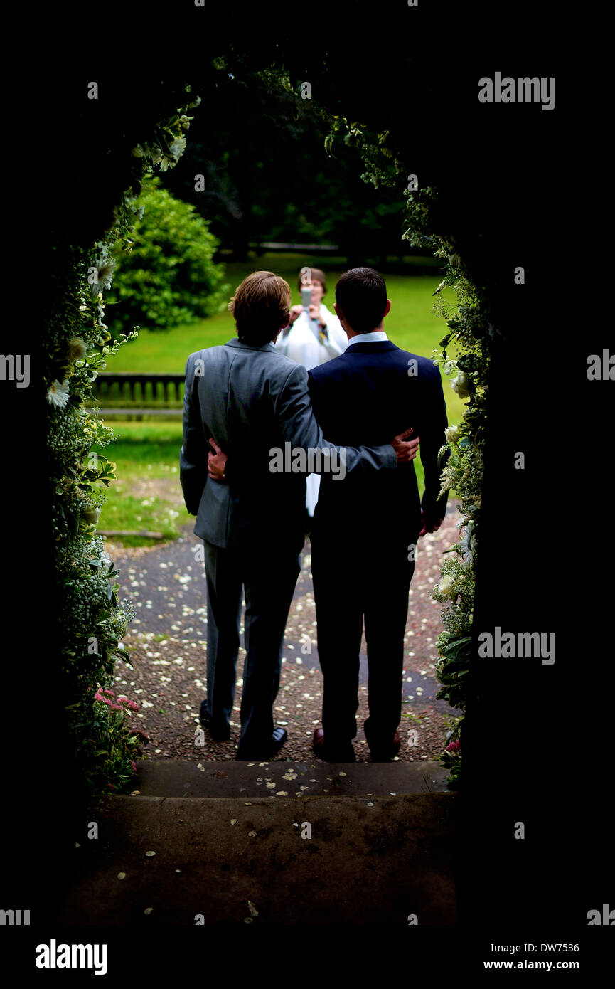 Schwule Paare gehen nach der Heiratszeremonie durch den Bogengang Stockfoto