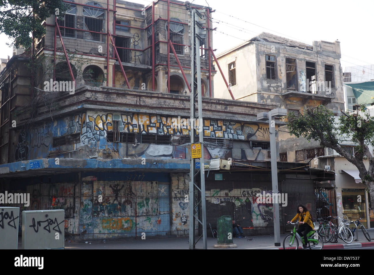 Radsportler entlang Allenby Street vor dem verlassenen Gebäude voller Graffiti in Tel Aviv Stockfoto