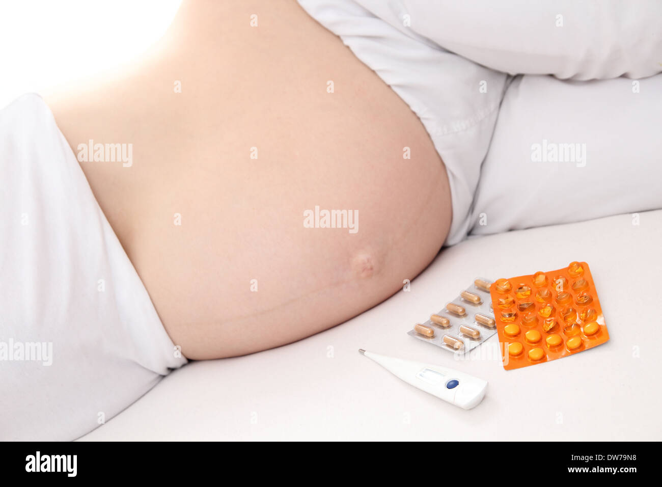 Schwangere Frauen mit Medikamenten im Bett Stockfoto