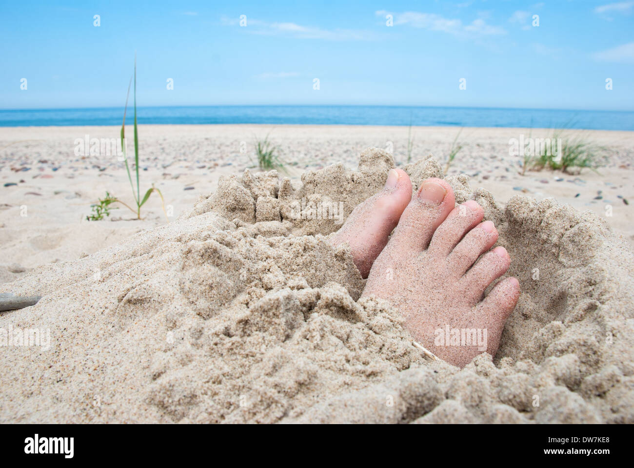 Füße im Sand mit ungedeckten Zehen an einem Strand begraben Stockfoto