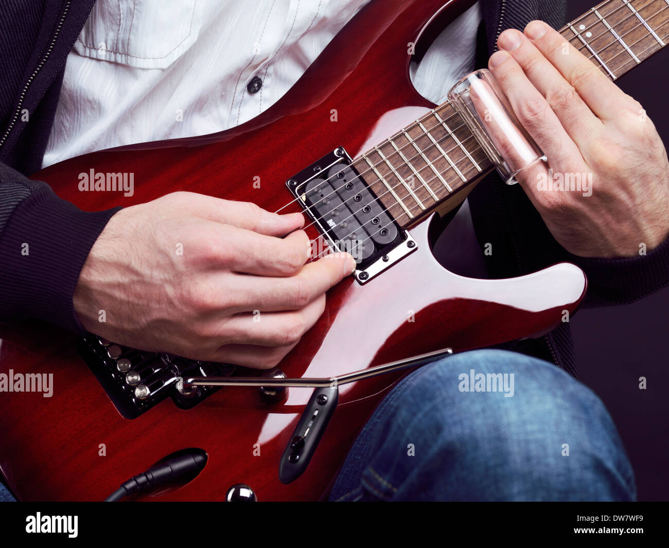 Führerschein und Fingerabdrücke bei MaximImages.com - Nahaufnahme von Männerhänden, die rote elektrische Gitarre mit einer Rutsche spielen Stockfoto