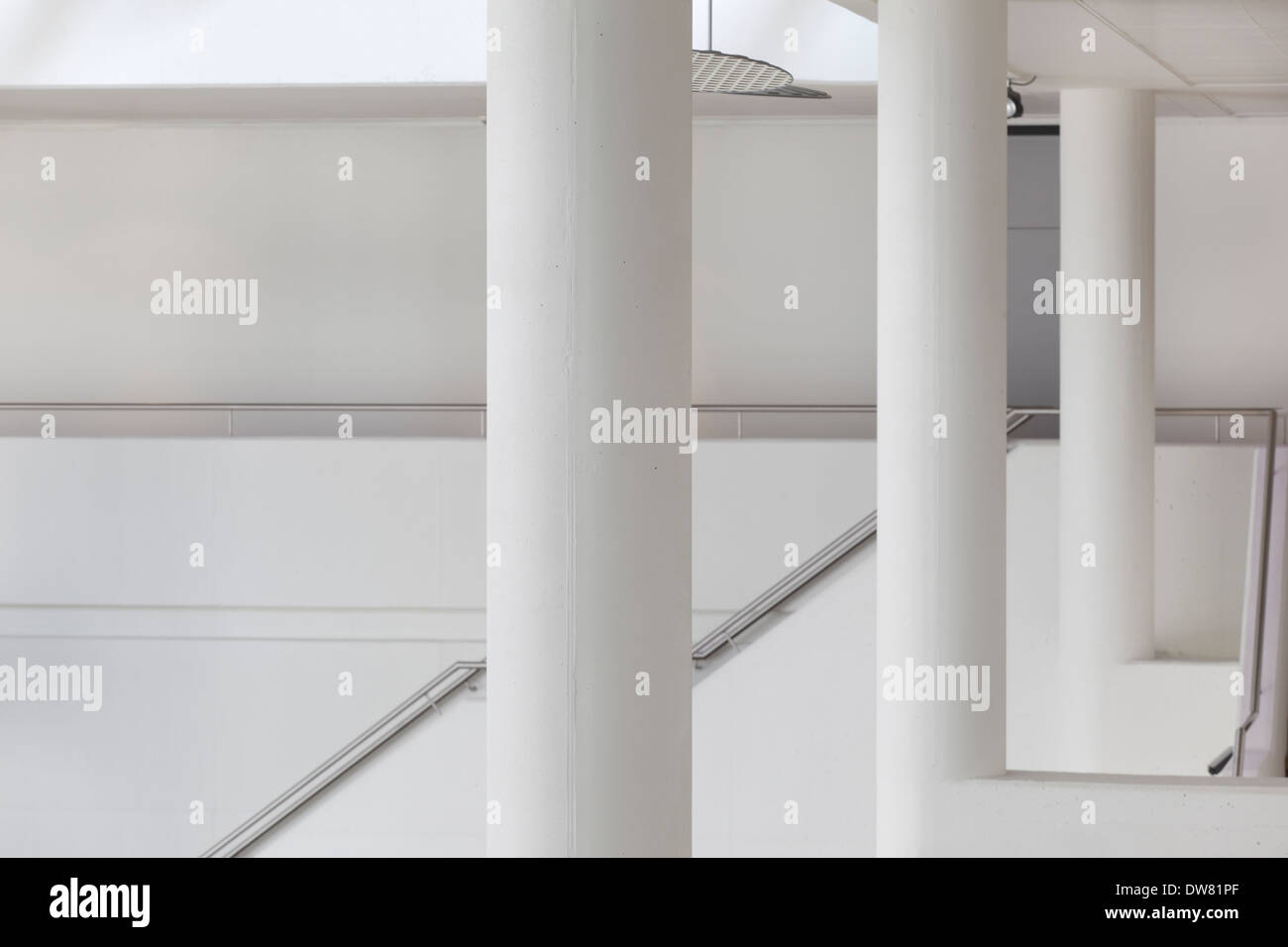 Genk Public Library, Genk, Belgien. Architekt: Claude Vasconi, 2008. Weiße Säulen und Wände im ersten Stock, mit Treppe desc Stockfoto