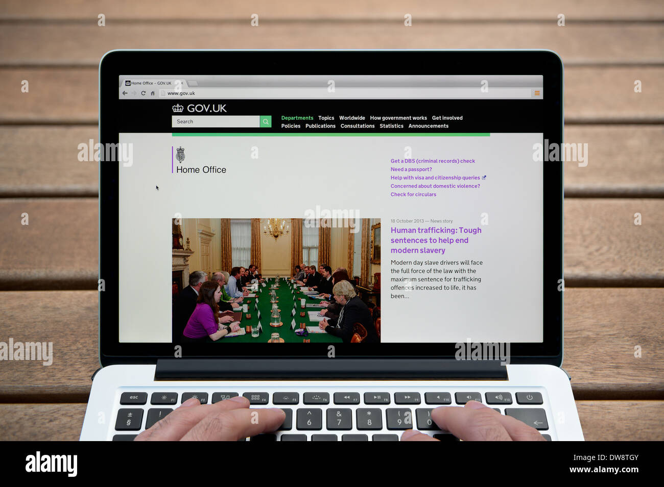 Home Office-Website auf einem MacBook Hintergrund eine Holzbank im Freien einschließlich eines Mannes Finger (nur zur redaktionellen Verwendung). Stockfoto