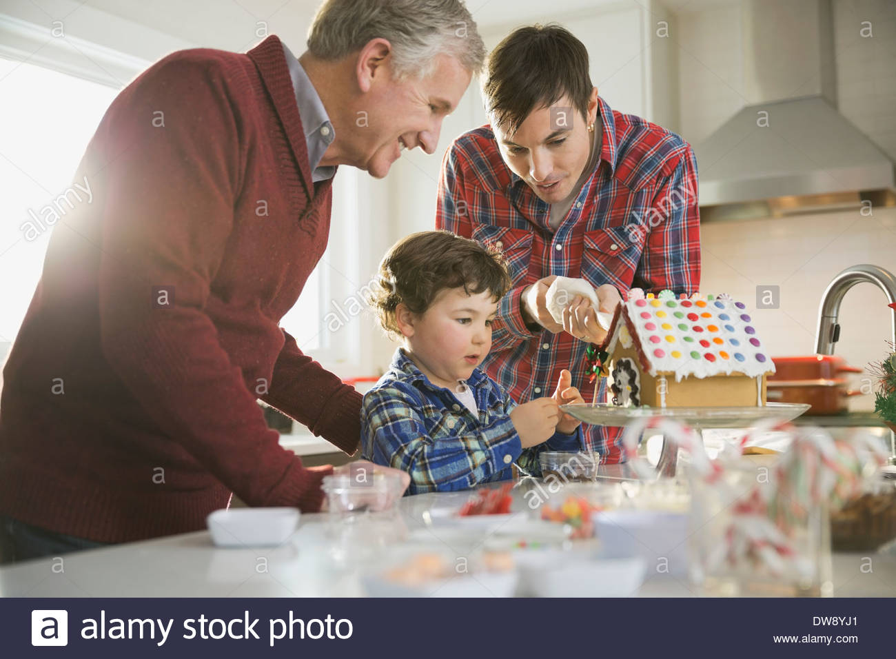 Drei Generationen Männchen Lebkuchenhaus zu Weihnachten dekorieren Stockfoto