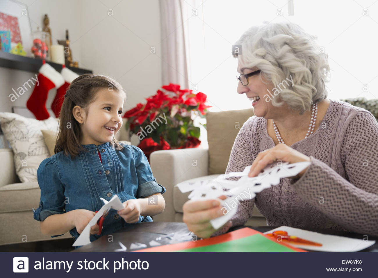 Großmutter und Enkelin machen Papier Schneeflocken Stockfoto