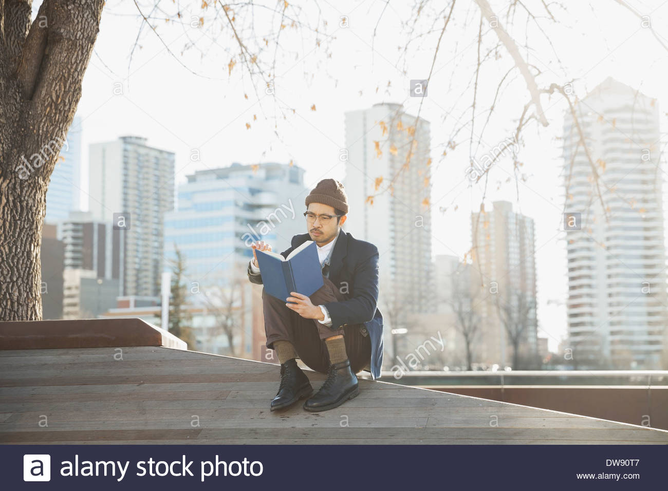 Mann liest Buch im freien gegen Stadtbild Stockfoto