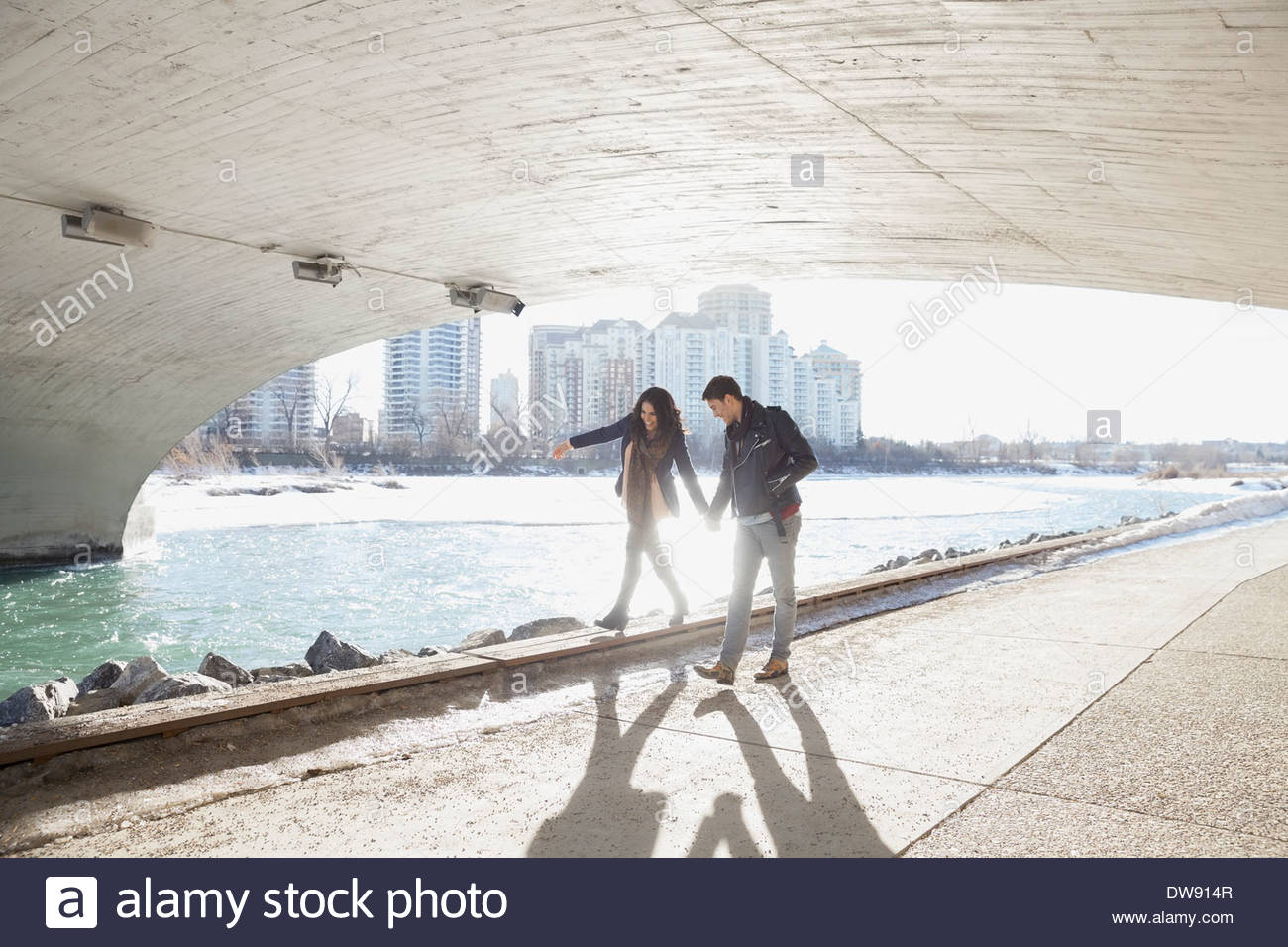 Mann, die Frau zu Fuß auf Fußweg unter Stadtbrücke zu unterstützen Stockfoto