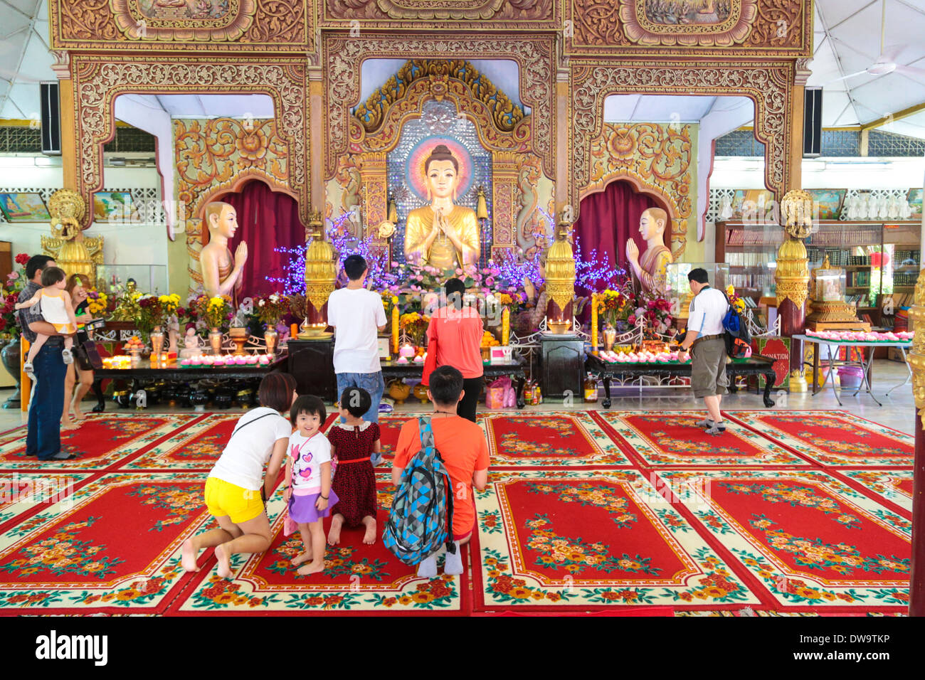 Familienmitglieder, die im Inneren der Dhammikarama, einem birmanischen buddhistischen Tempel in Penang Malaysia beten. Stockfoto