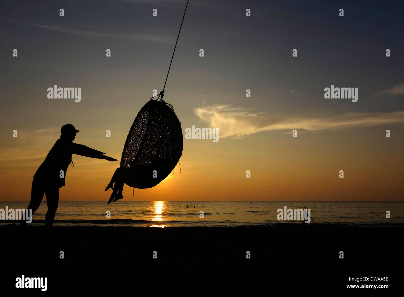 Spielen in einem Seil Schwung bei Sonnenuntergang an einem Strand auf der Insel Koh Kood, Thailand. Stockfoto