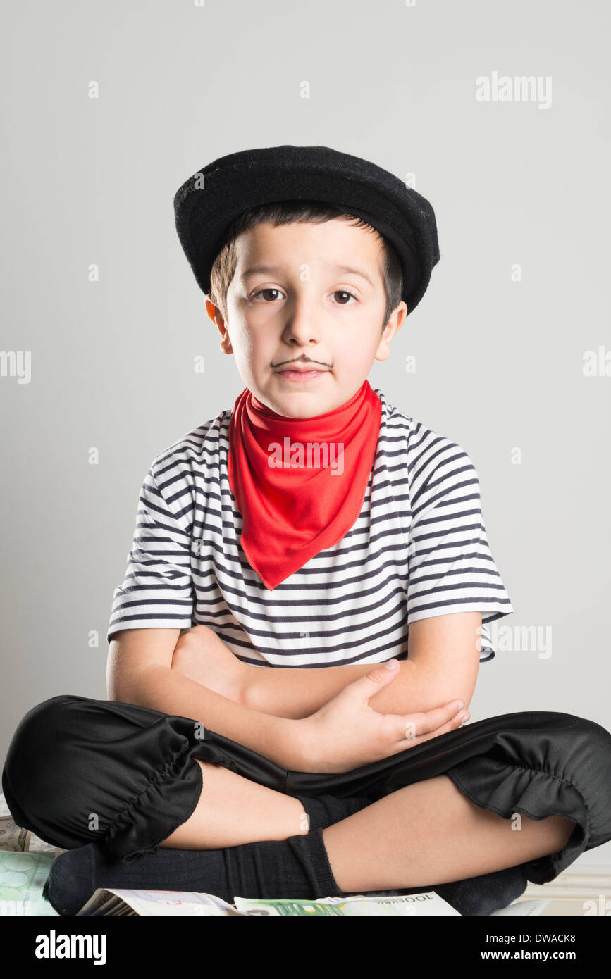 Kind verkleidet als ein Räuber mit einem gestreiften Oberteil, schwarzer Hut und schlecht gezeichnete Schnurrbart Stockfoto