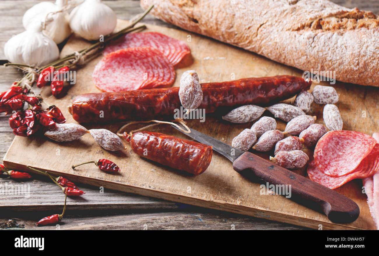 Satz von Salami Wurst mit frisches Brot, Knoblauch und red hot Chili Peppers auf Holzbrett serviert. Stockfoto