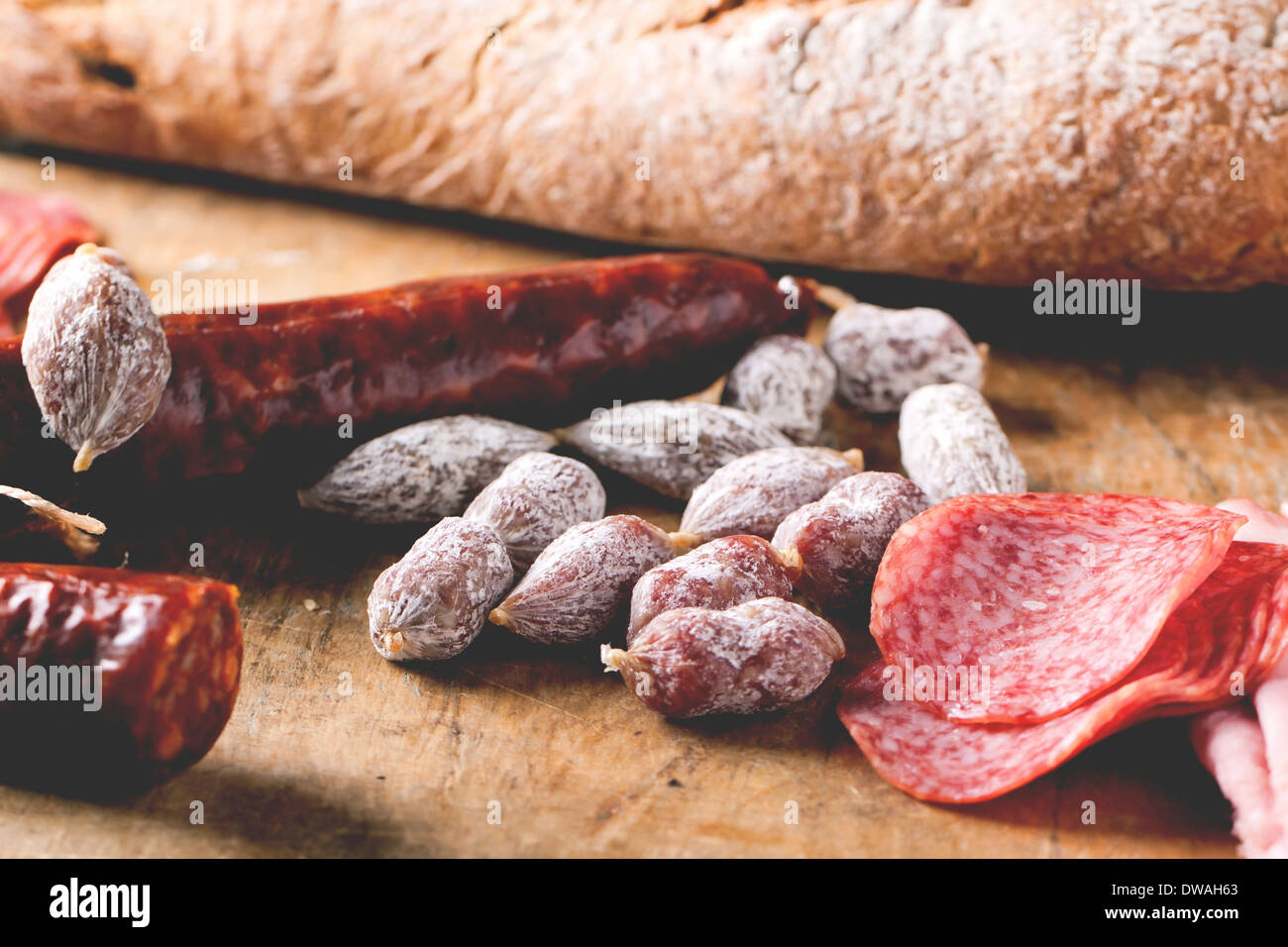 Satz von Salami serviert mit frischem Brot auf alten Holzbrett. Stockfoto