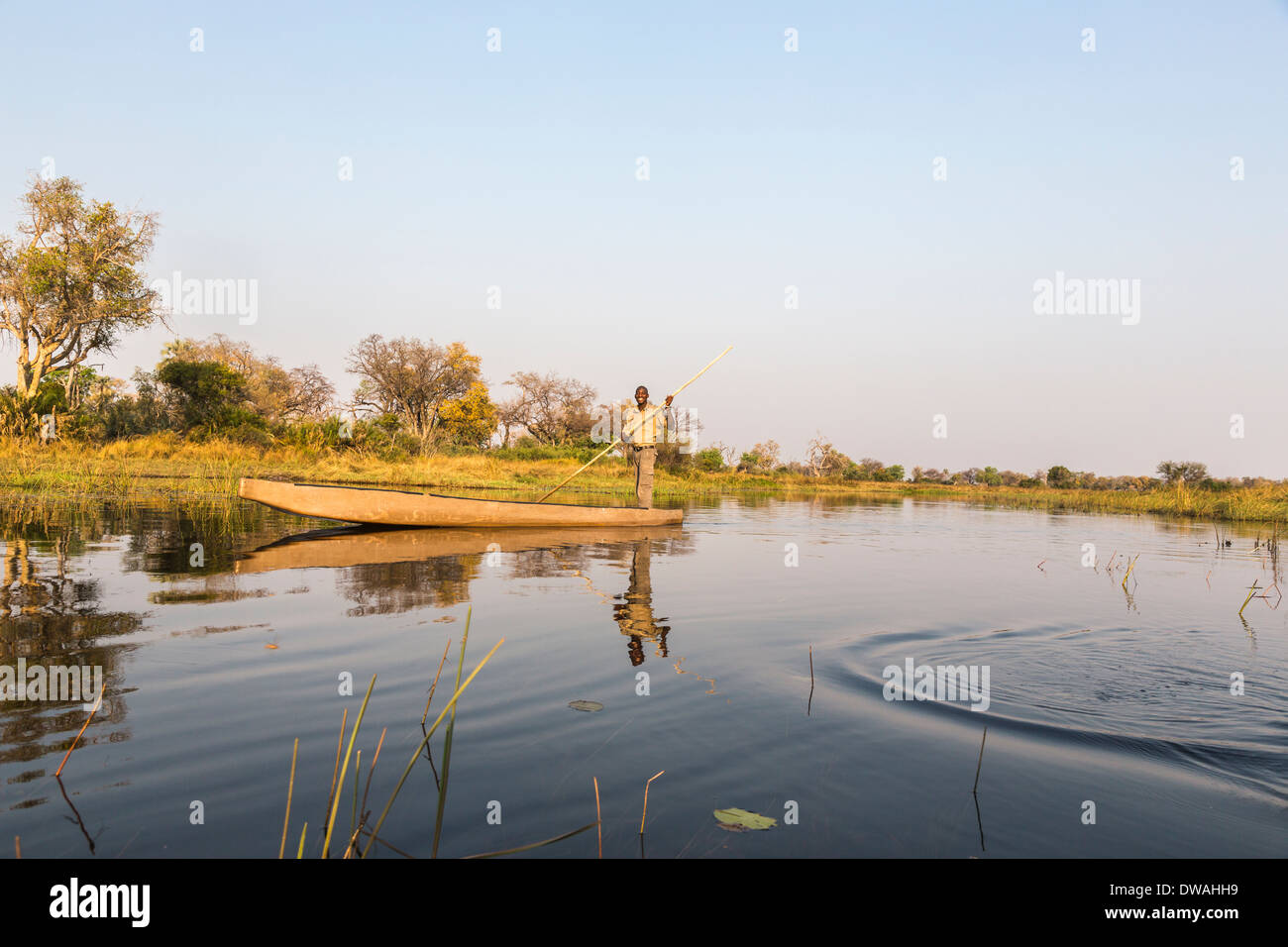 Friedliche Mokoro Boot mit Guide am Fluss mit Reflexionen im Xigera Camp in das Okavango Delta, Botswana, Südafrika Stockfoto