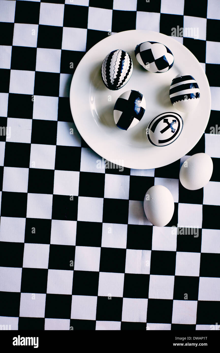 Kreative Ostereier auf Teller mit zwei weißen Eiern in der Nähe von Schach Hintergrund Stockfoto